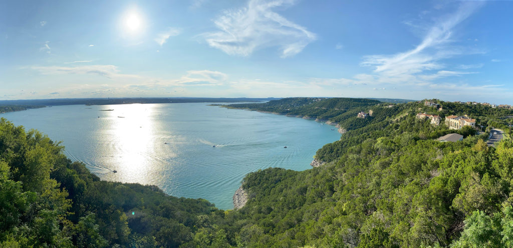 panoramic view of the lake travis surrounded with trees from a view point under cloudy sky in austin